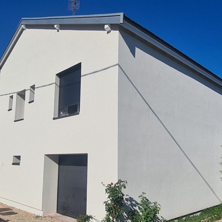 Façade d'une maison récemment isolée par l'extérieur avec enduit de finition, illustrant une isolation thermique performante et esthétique."